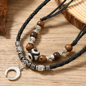 Macro detail of hand-woven cord necklace with vintage wooden beads and crescent pendant