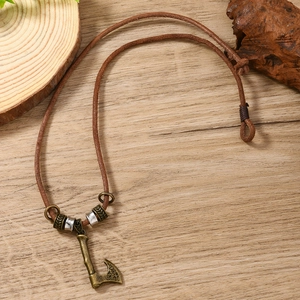 Close-up of vintage Viking axe pendant with leather cord on a rustic wooden surface