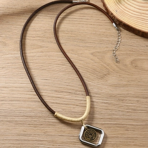 Collana vintage intrecciata con ciondolo in moneta di rame su sfondo in legno