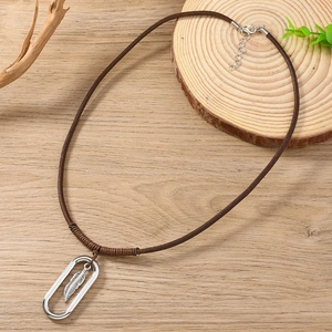 Detail of adjustable leather cord necklace featuring a silver feather pendant on wood