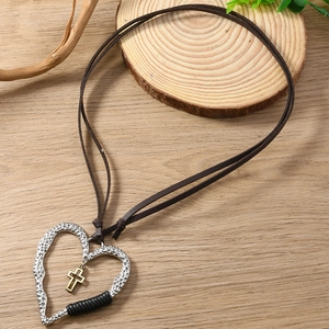 Détail du collier cœur vintage avec croix dorée sur décor en bois rustique