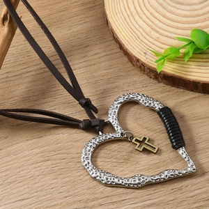 Détail du pendentif cœur martelé en argent avec croix dorée sur cordon en cuir brun