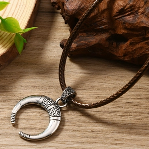 Gros plan d'un pendentif lune rétro argenté avec motifs tribaux sur cordon marron