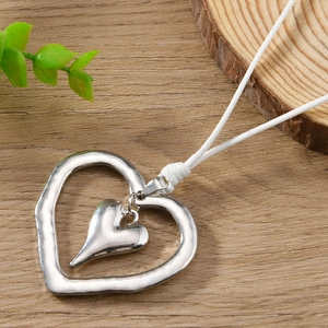 Détail du pendentif double cœur argenté avec texture martelée sur cordon blanc