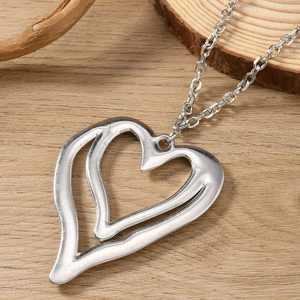 Silver hollow heart pendant necklace with double-layer design on a rustic wooden background