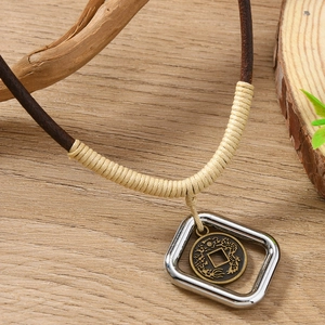 Dettaglio macro della collana con ciondolo retrò e drago inciso su fondo in legno