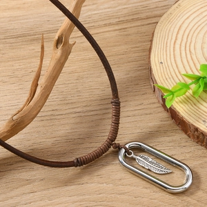 Vintage braided leather sweater necklace with silver feather pendant on wood background
