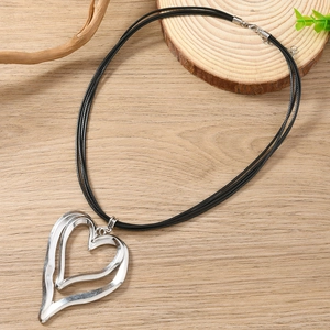 Close-up of double-layer hollow heart pendant on black cord over natural wood