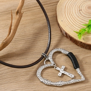 Détail du pendentif cœur vintage avec croix et cordon en cuir marron rustique