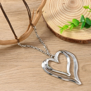 Detail of silver double heart pendant on brown wax cord with rustic wooden background