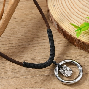 Collier pendentif hibou vintage avec cordon en cuir marron foncé sur fond de bois