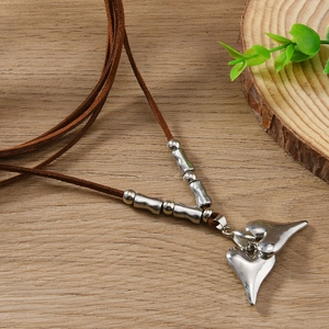 Detail of silver double heart pendant on brown cord necklace over wooden surface