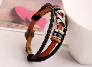 Detail of vintage multilayer leather bracelet with metal cross charm and snap buttons