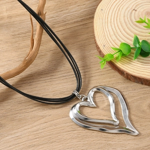 Double heart pendant necklace with silver alloy finish and black cord on wooden background
