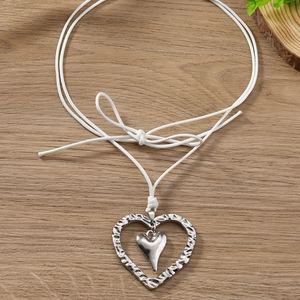 Détail du pendentif double cœur argenté avec texture martelée sur cordon blanc