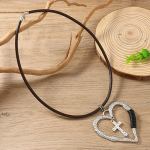 Collier rétro en cuir avec pendentif cœur et croix sur fond en bois naturel