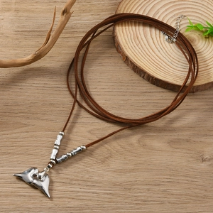 Bohemian silver heart pendant necklace with brown suede cord on natural wood background