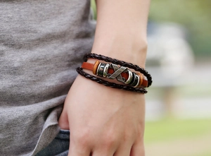 Detailed close-up of multilayer leather bracelet with metal X symbol on wrist
