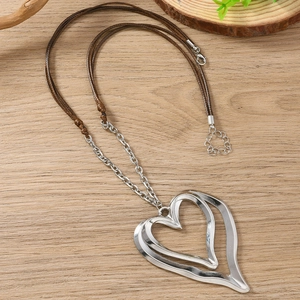 Vintage hollow double heart pendant necklace with brown braided rope on wooden surface