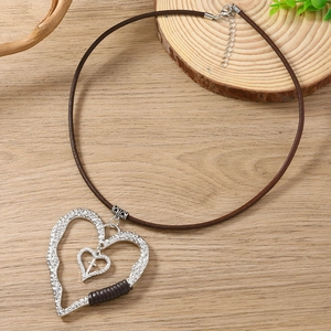 Gros plan du pendentif cœur vintage avec texture martelée et croix sur cordon en cuir
