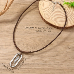 Retro leather necklace with a silver feather pendant in an oval frame on a wooden surface
