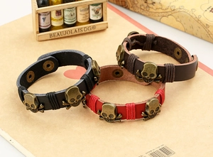 Three punk leather bracelets with bronze skulls in black, red, and brown tones