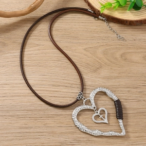 Détail du pendentif cœur argenté avec texture martelée et croix sur cordon en cuir