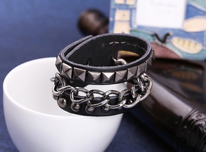 Detail eines Punk Lederarmbands mit schwarzen Pyramidennieten und Metallkette