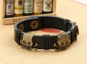 Detail of punk leather bracelet featuring bronze skull studs and metal snap closure