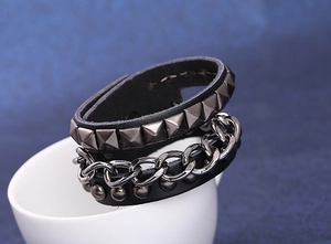 Detail eines schwarzen Lederarmbands im Punk-Stil mit silbernen Pyramiden-Nieten und Kette
