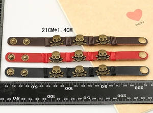 Detailed view of punk skull leather bracelets in brown red and black with size ruler