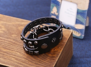 Makroansicht schwarzes Punk-Lederarmband mit Metallnieten, quadratischen Spikes und Kette