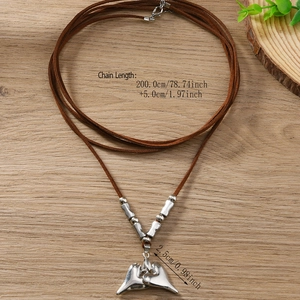 Silver heart pendant necklace with long brown cord on a light wood background