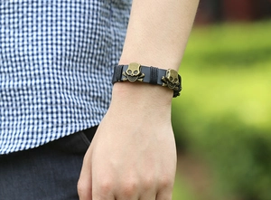Close-up of punk black leather bracelet with bronze skulls on a person's wrist