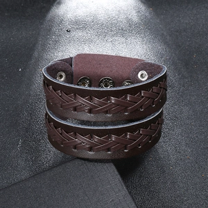 Close-up of wide brown braided leather bracelet with adjustable silver snap buttons