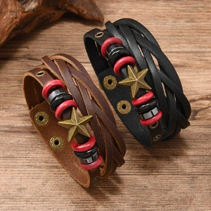 Vintage woven leather bracelet set with bronze star charm on a rustic wooden background