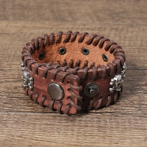 Macro shot of a vintage brown leather punk bracelet with skull studs on dark wood