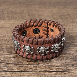 Detailed view of punk leather bracelet with row of metal skulls and hand-stitched edges