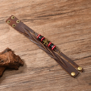 Macro shot of vintage woven leather bracelet with star charm on rustic wood background