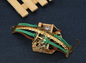 Dettaglio del bracciale intrecciato multistrato con ciondolo Love, croce e chiusura a moschettone