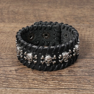 Close-up of black leather punk bracelet with silver skull rivets on wood background