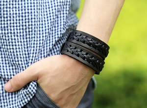 Close-up of a double-layered black woven leather bracelet worn on a male wrist outdoors