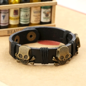Punk leather bracelet with bronze skulls and adjustable metal snaps on wood background