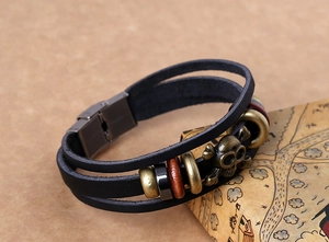 Detail of vintage bronze skull and beads on multilayer black leather men's bracelet