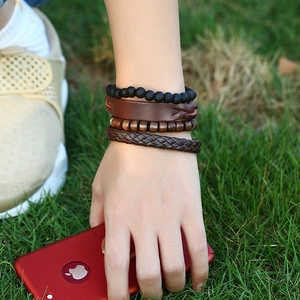 Set of four vintage braided leather and beaded bracelets for men on natural background
