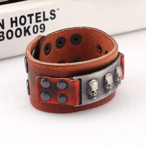 Macro detail of punk rock brown leather bracelet with three silver skull metal ornaments