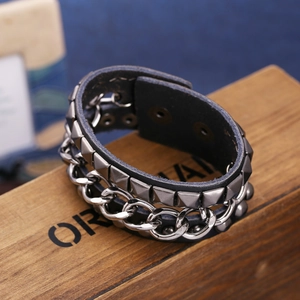 Punk-Lederarmband mit Pyramidennieten und grober Silberkette auf rustikalem Holzständer