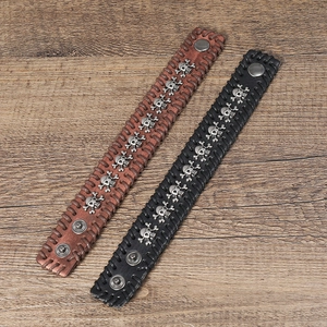 Detail of vintage punk leather bracelets featuring metal skulls and woven edge stitching