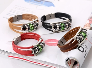 Detail of multilayer leather bracelets with green beads and metallic press buckles
