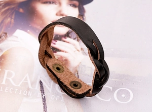 Détail d'un bracelet en cuir tressé avec double boutons-pression et structure en couches